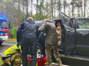 Zdjęcie przedstawia miejsce zdarzenia drogowego. Policjantów, ratowników i strażaków.