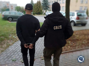 Zatrzymany mężczyzna prowadzony przez policjanta