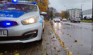 Zdjęcie przedstawia fragment radiowozu i ulicę.