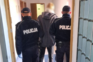 Zdjęcie przedstawia zatrzymanego mężczyznę i umundurowanych policjantów.