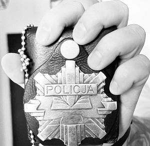 Zdjęcie przedstawia fragment policjanta z odznaką.