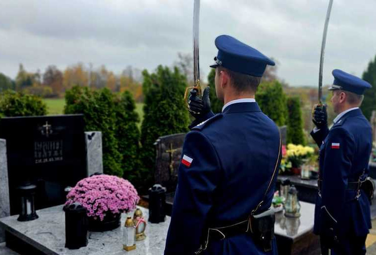 Policjanci na cmentarzu stojący przed grobami