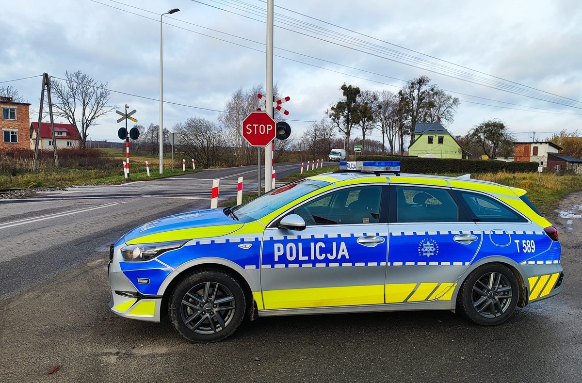 Policyjny radiowóz w pobliżu przejazdu kolejowego.