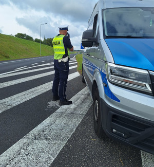 Zdjęcie przedstawia fragment policjanta kontrolującego prędkość.