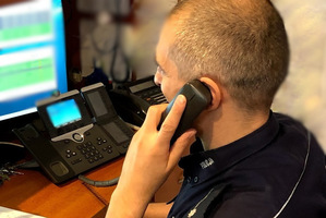 Policjant przy komputerze, rozmawiający przez telefon.