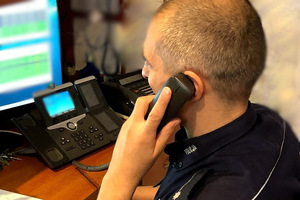 Policjant przy komputerze, rozmawiający przez telefon.