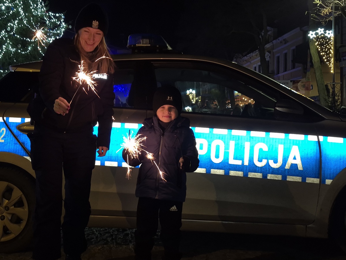 Policjantka i dziecko przy radiowozie.