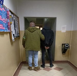 policjant prowadzi zatrzymanego