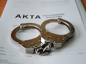 Zdjęcie przedstawia kajdanki oraz teczkę.