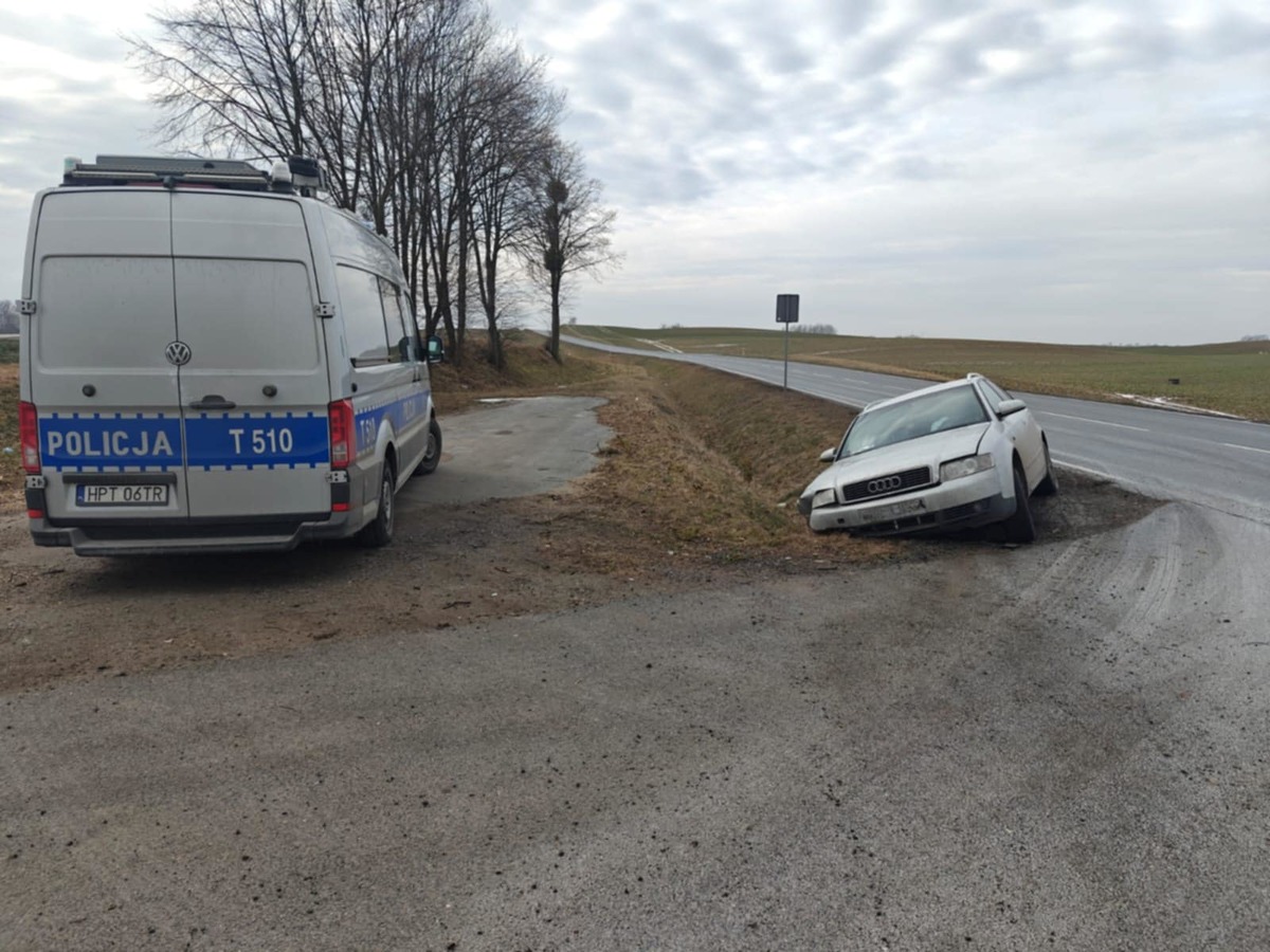 Miejsce zdarzenia drogowego. Policyjny radiowóz i auto w przydrożnym rowie.