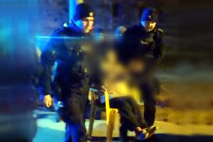 Policjanci niosący kobietę siedzącą na krześle