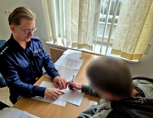 Policjant i mężczyzna przy biurku