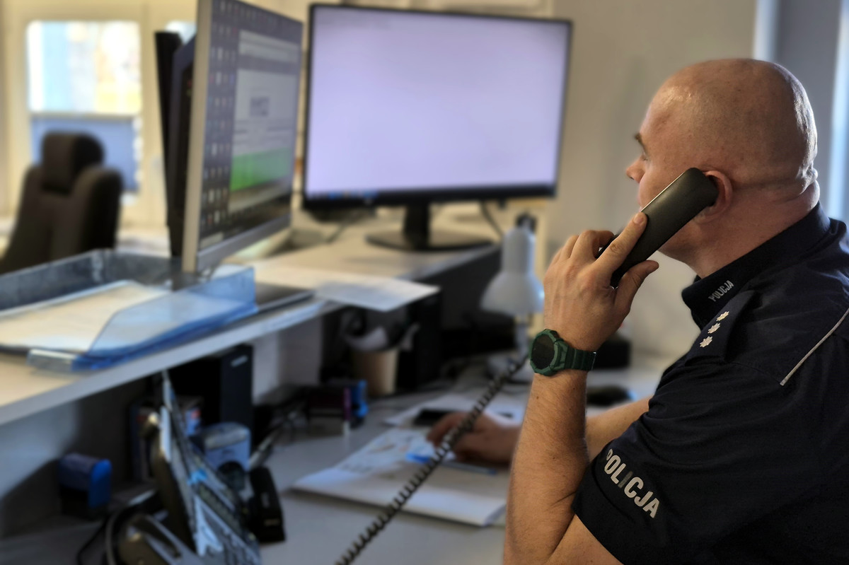 kom. Tomasz Olender siedzący za biurkiem i rozmawiający przez telefon