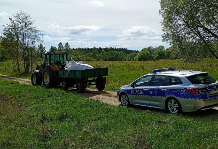 Policyjni radiowóz i ciągnik z przyczepą