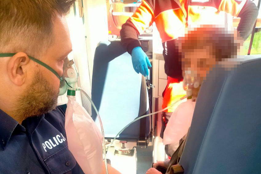 asp. Artur Gudaniec i uratowany mężczyzna w karetce z maskami tlenowymi na twarzach