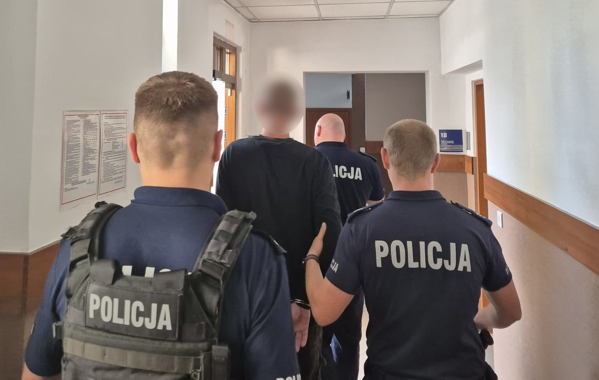 Zatrzymany mężczyzna i policjanci w budynku.