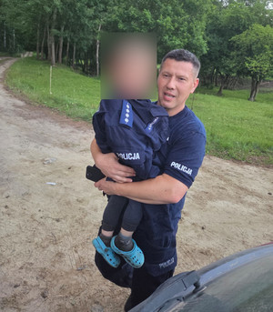 Policjant trzymający na rękach chłopca.