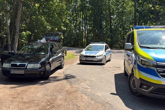 Miejsce kontroli samochodu, dwa radiowozy i auto osobowe na leśnym parkingu