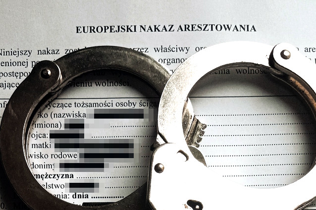 Kajdanki leżące na kartce z napisem Europejski Nakaz Aresztowania