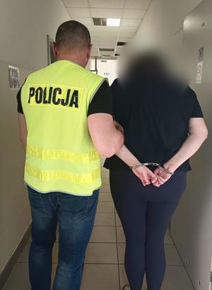 zatrzymana kobieta prowadzona przez policjanta