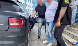 Zatrzymany mężczyzna prowadzony przez policjantów