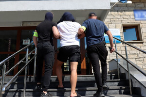Zatrzymany mężczyzna prowadzony przez policjantów
