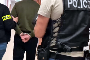 Zatrzymany mężczyzna prowadzony przez policjantów