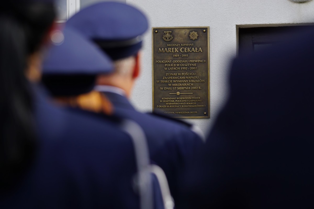 Uczestnicy uroczystego spotkania przed tablicą upamiętniającą poległego policjanta