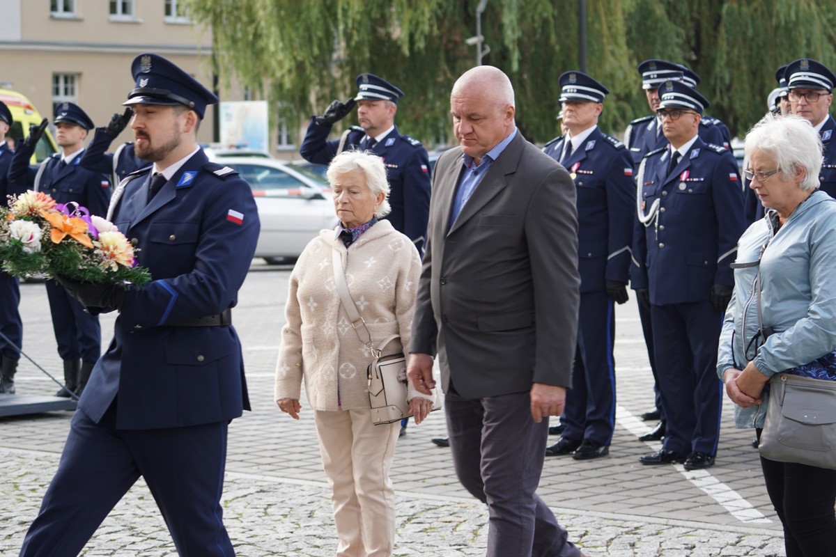 Uczestnicy uroczystego spotkania przed tablicą upamiętniającą poległego policjanta