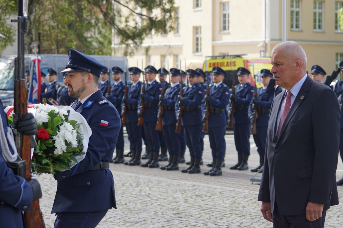Uczestnicy uroczystego spotkania przed tablicą upamiętniającą poległego policjanta
