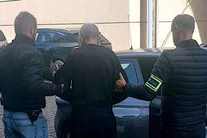 Zatrzymany mężczyzna prowadzony przez policjantów