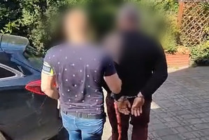 Zatrzymany mężczyzna prowadzony przez policjanta