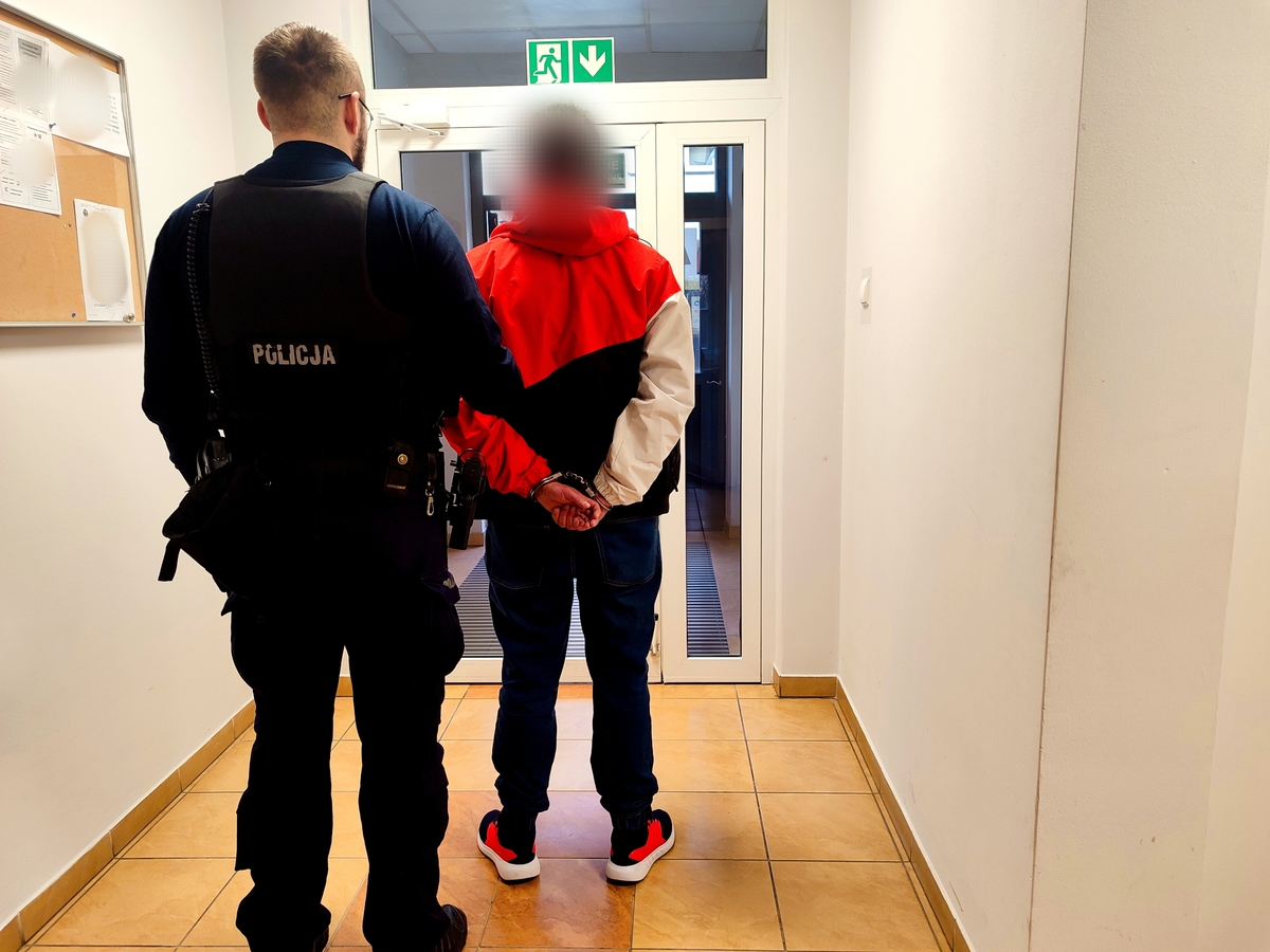 policjant prowadzi osobę zatrzymaną