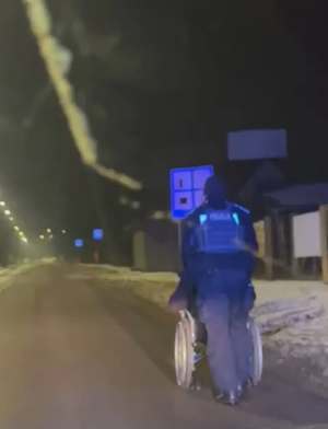 Policjant pomaga osobie poruszającej się na wózku inwalidzkim.