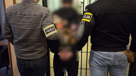 Policjanci prowadzący zatrzymanego mężczyznę.