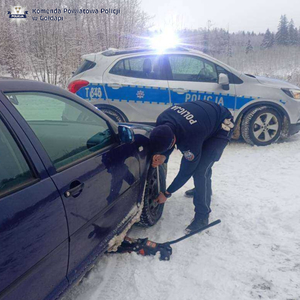 Policjant wymienia koło w aucie