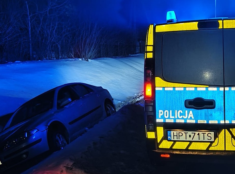 Pojazd w przydrożnym rowie i radiowóz.