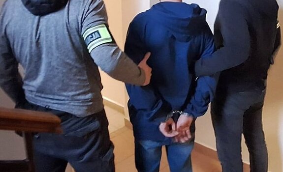 policjanci prowadzą zatrzymanego