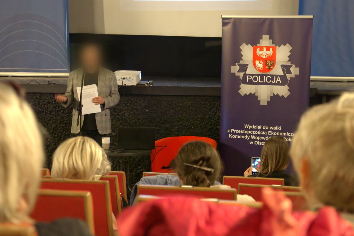 Policjant prowadzi szkolenie na tle baneru Komendy Wojewódzkiej Policji