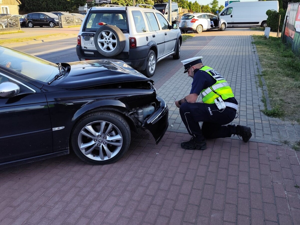 Policjant ruchu drogowego podczas oględzin pojazdu na miejscu zdarzenia drogowego
