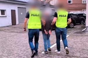 Zatrzymany mężczyzna prowadzony przez policjantów