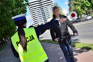 Policjantka ruchu drogowego zatrzymuje kierującego hulajnogą przy użyciu tarczy do zatrzymywania