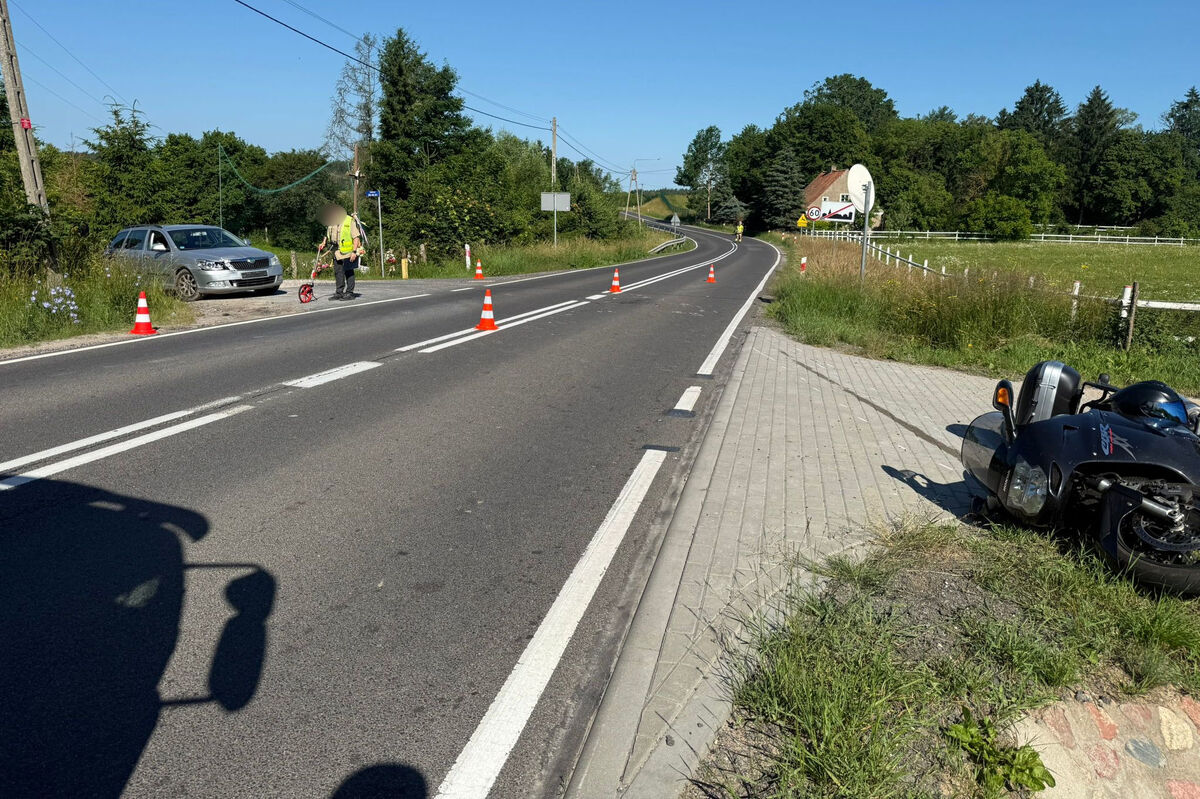 po lewej stronie uszkodzony pojazd, przed nim policjant kryminalny podczas czynności procesowych, po prawej stronie wywrócony motocykl