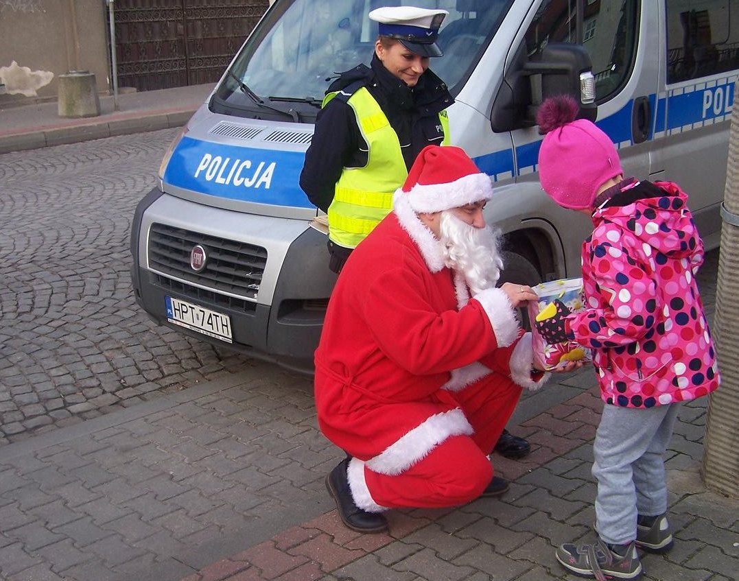 Policjantka z Mikołajem przekazują drobne upominki pieszym