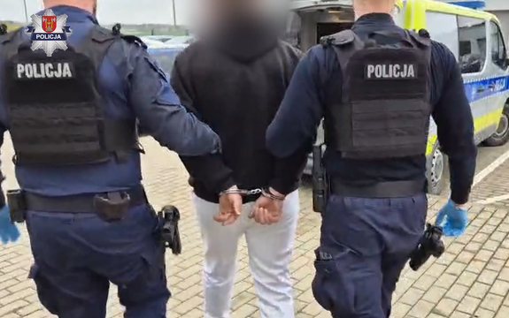 umundurowani policjanci w trakcie doprowadzania do oznakowanego radiowozu zatrzymanego 47-latka, który ma na rekach założone kajdanki